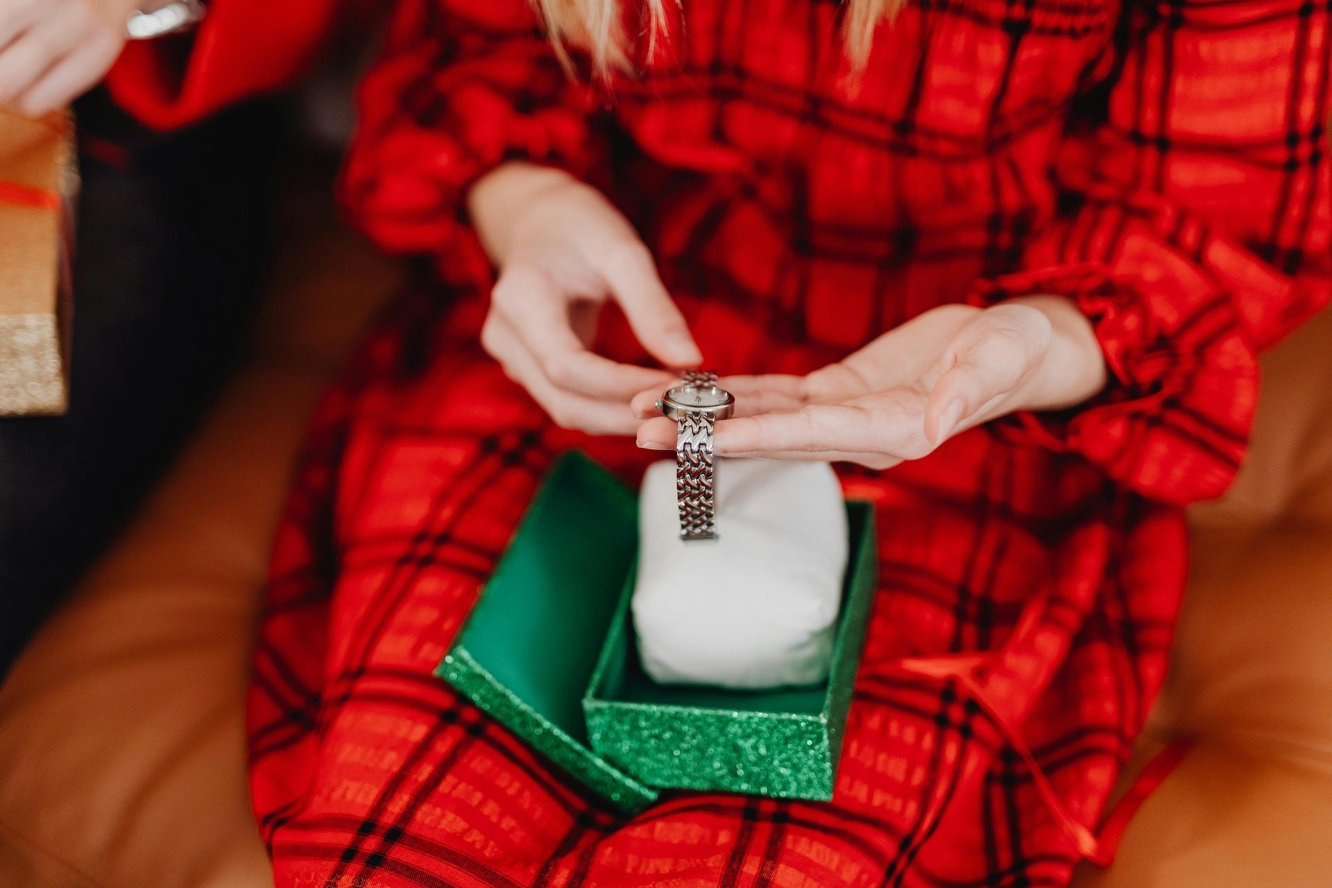 Woman holding a silver classic watch from a green gift box.