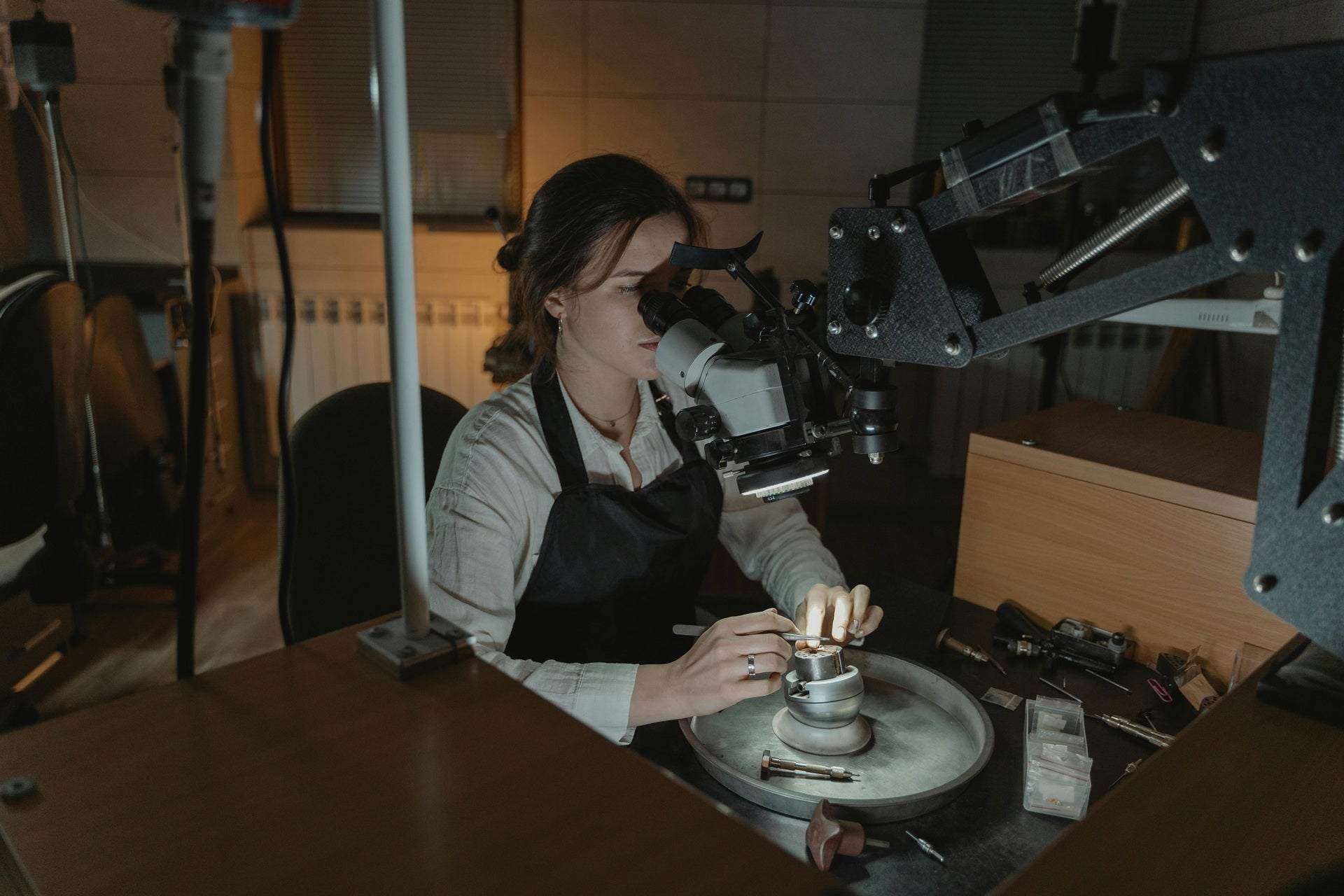 Independent jewelry designer in Chicago examining a gemstone under a microscope.