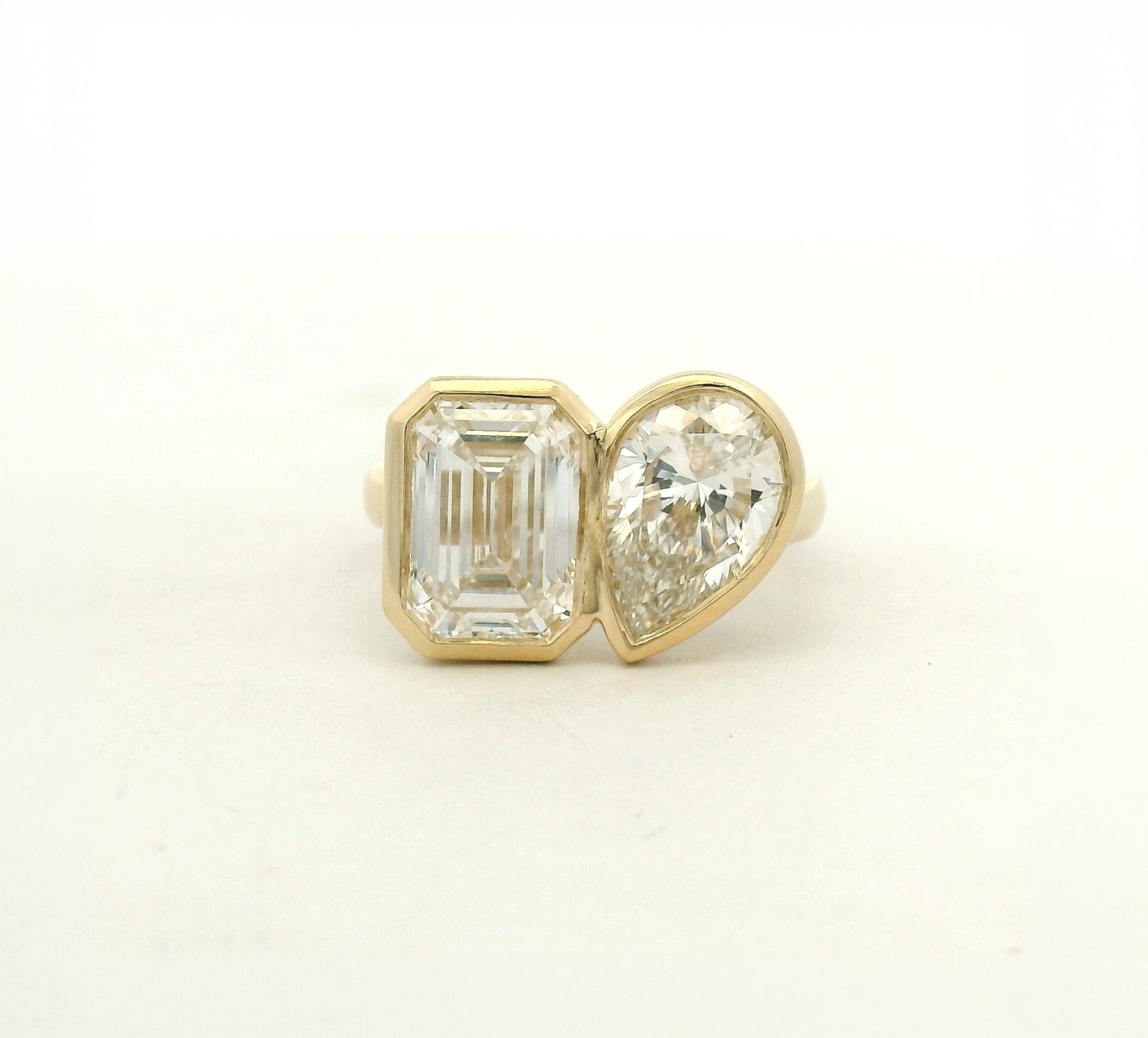 14k yellow gold toi et moi style engagement ring with an emerald and a pear cut diamond