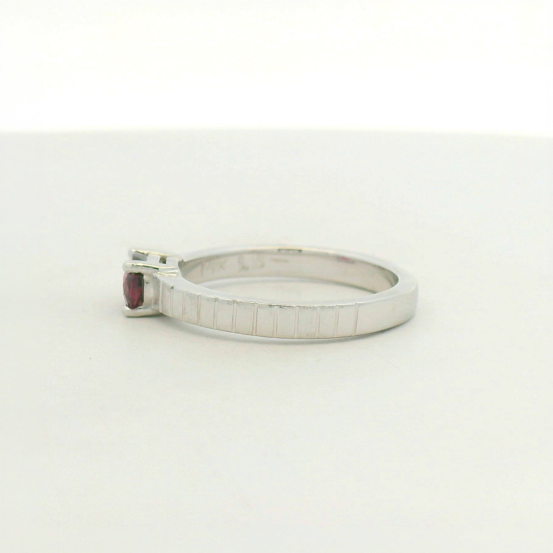 14kt white gold east west set ruby with banded texture on shank