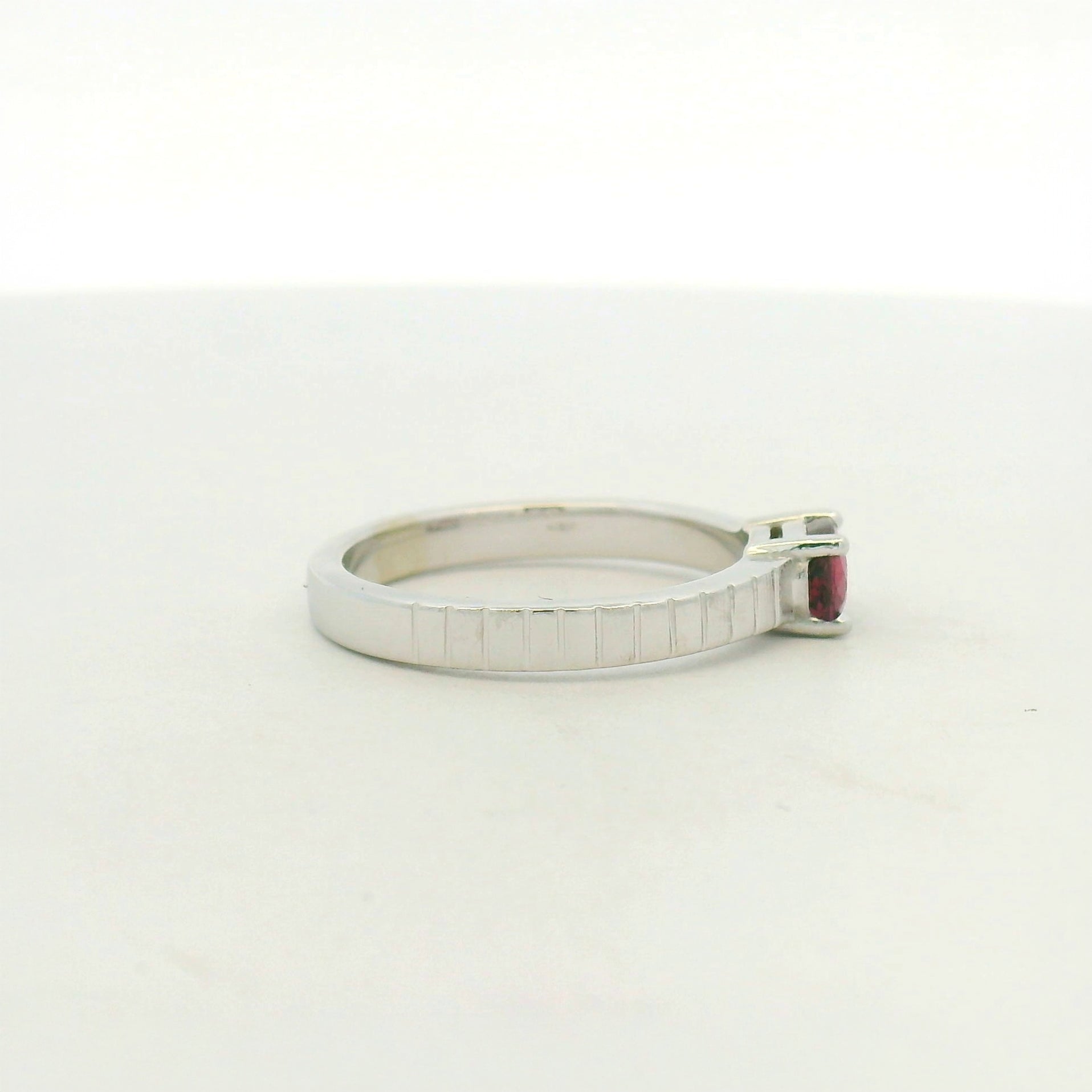 14kt white gold east west set ruby with banded texture on shank