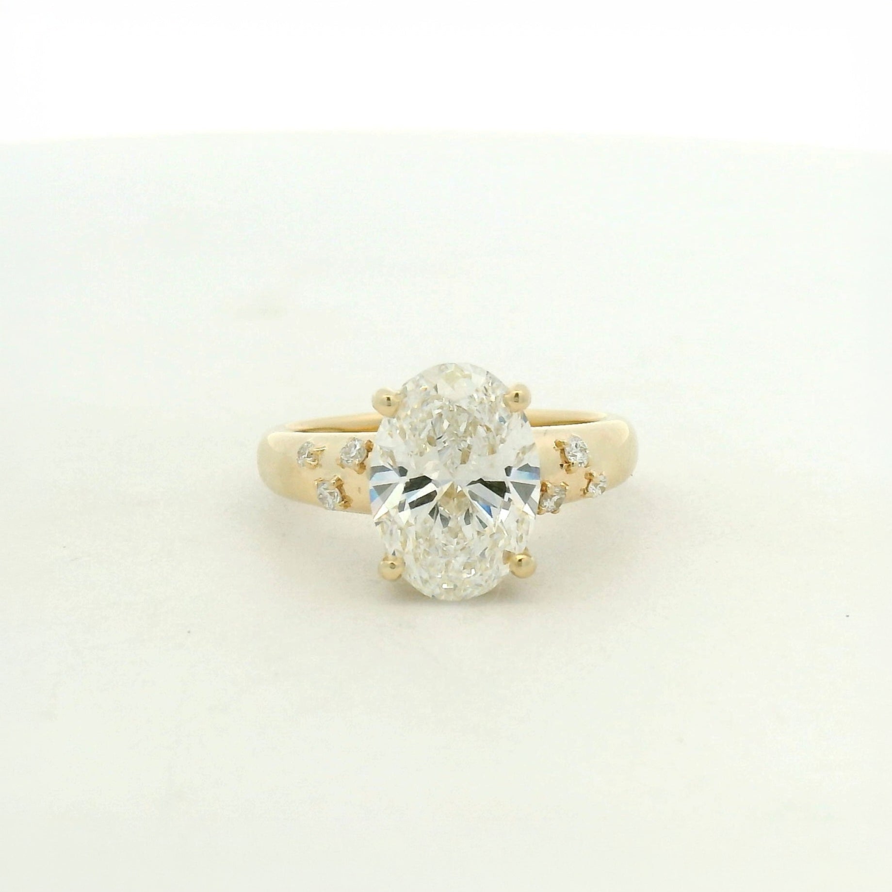 14kt yellow gold with a large center oval and asymetrical mellie side stones