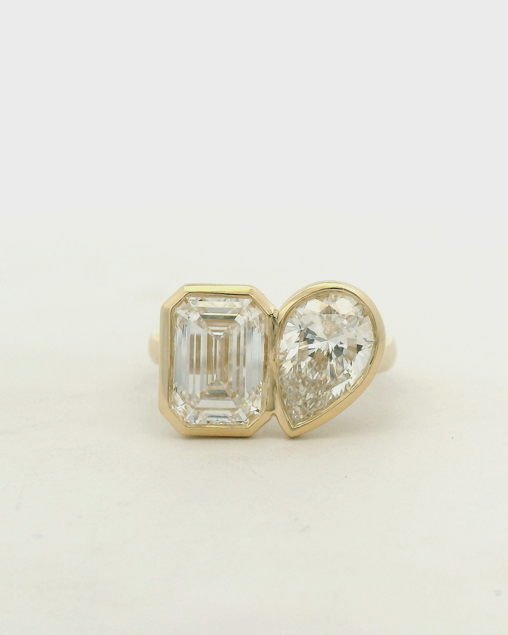 14k yellow gold toi et moi style engagement ring with an emerald and a pear cut diamond