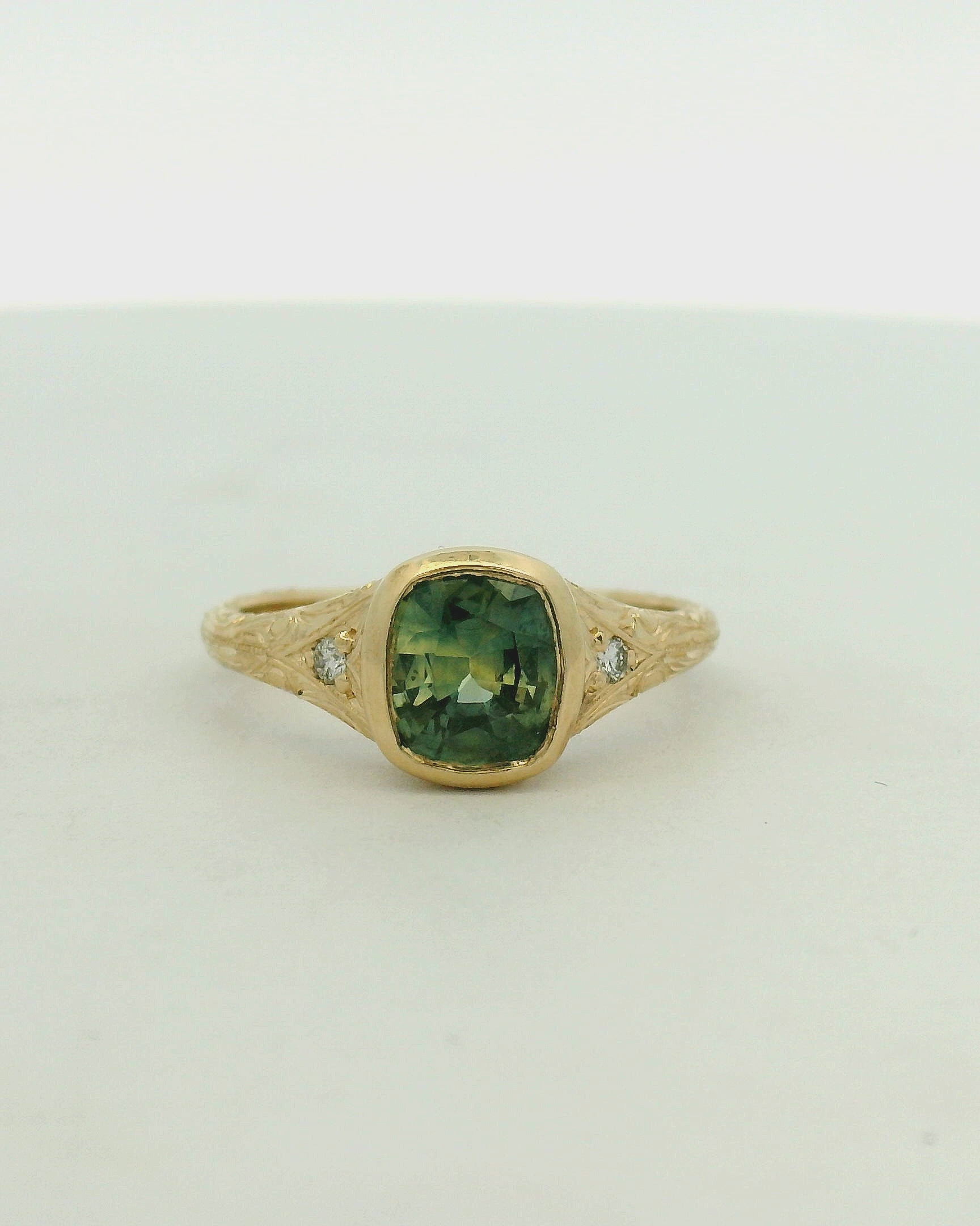 14k yg bezel cushion sapphire ring with small stones and hand engraving