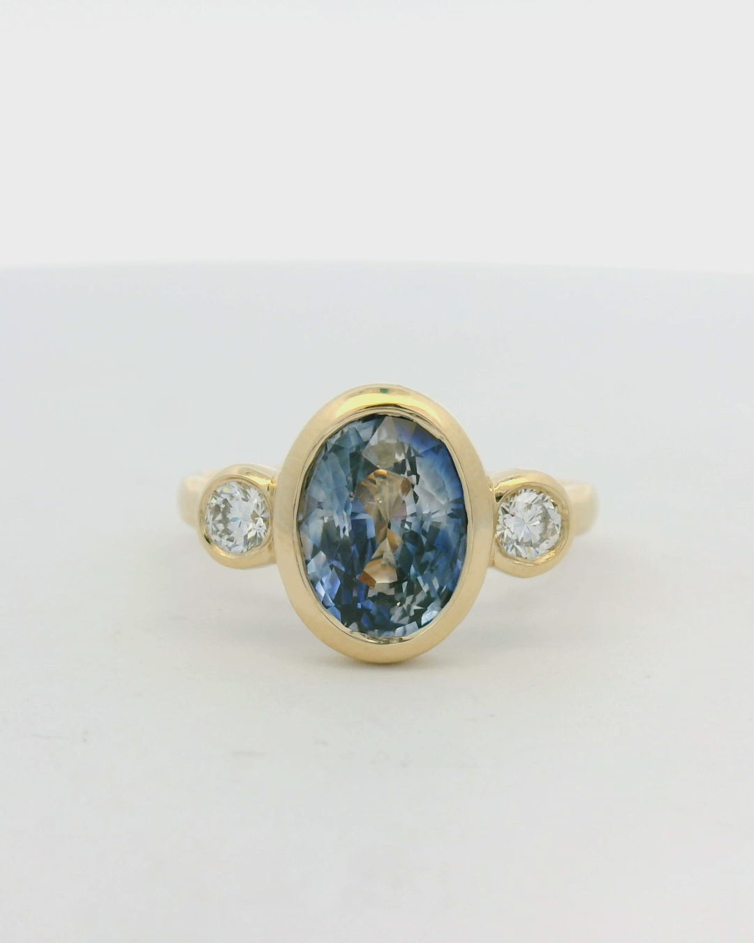 14KT yellow gold bezel set three stone sapphire and diamond engagement ring