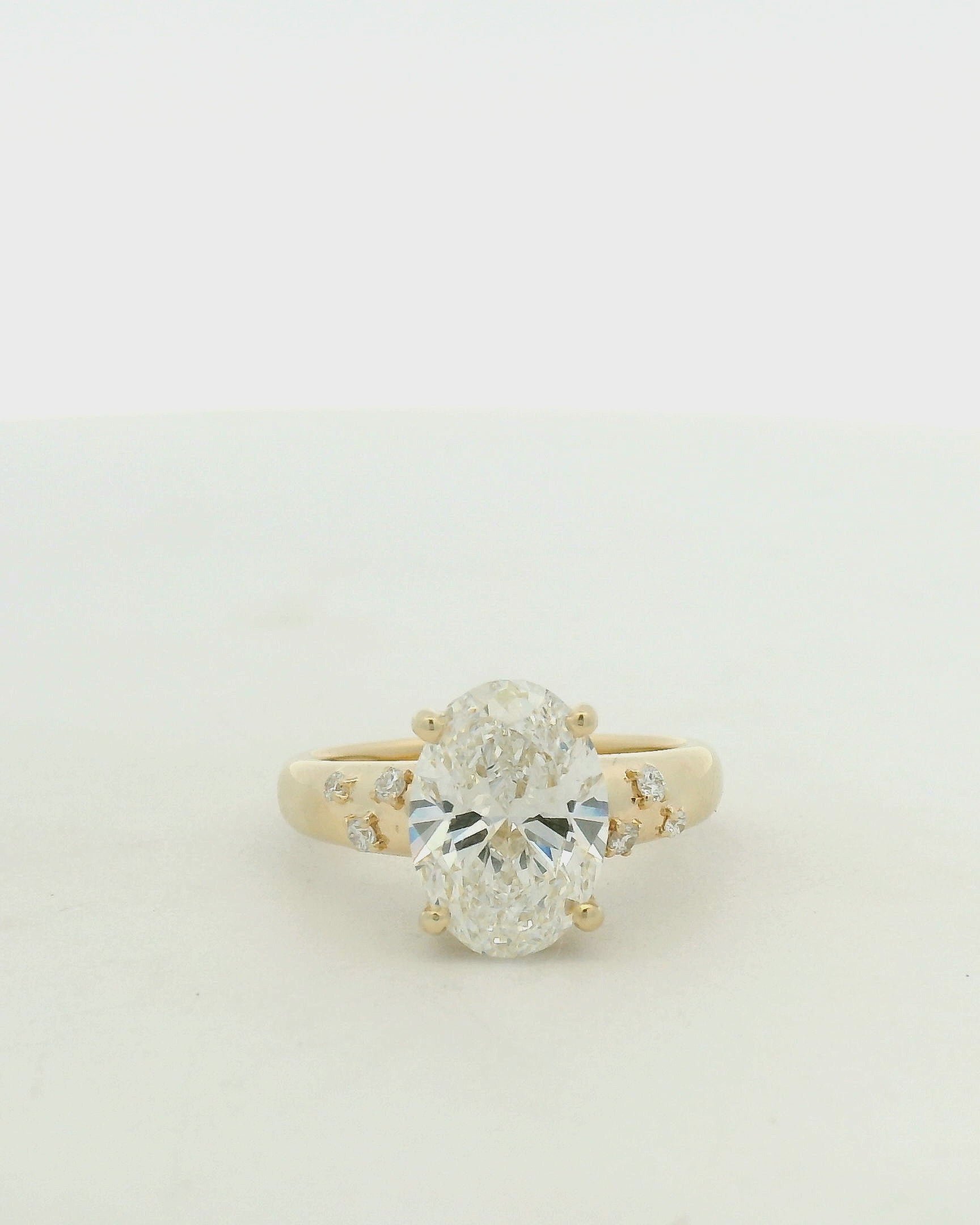 14kt yellow gold with a large center oval and asymetrical mellie side stones